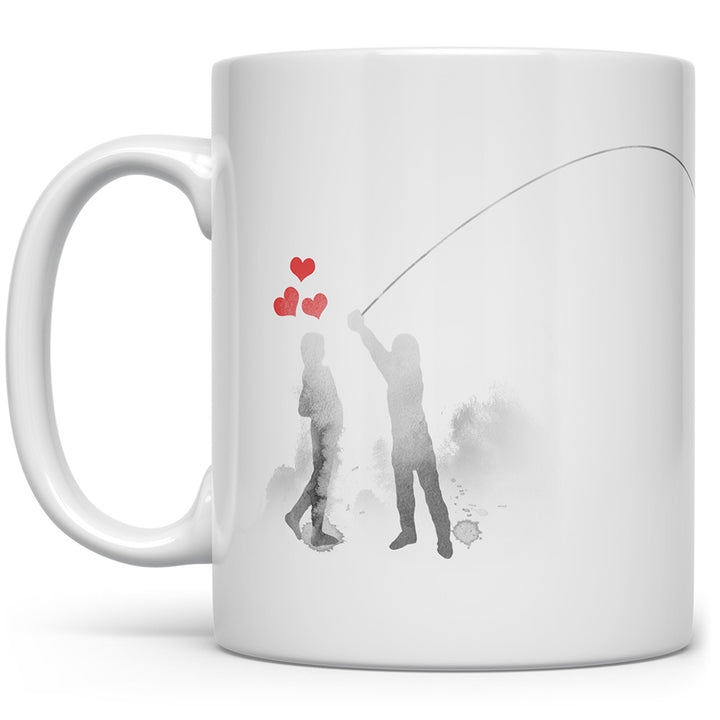 White mug with people lassoing the moon and red hearts