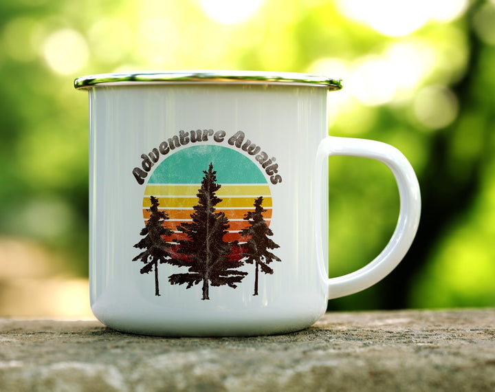 Camp mug with adventure awaits over sunset with 3 pine trees in front.