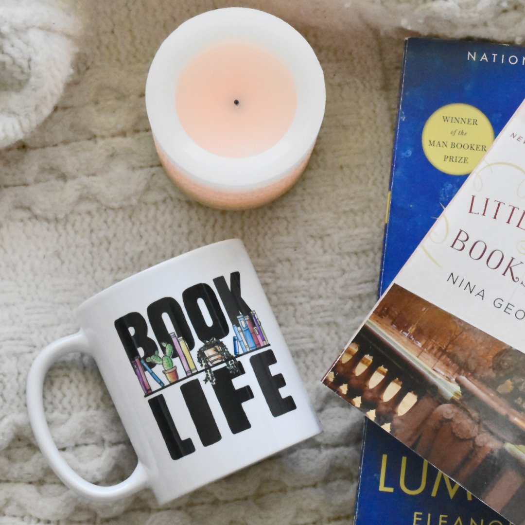 Book Life Mug on a table next to books and a candle