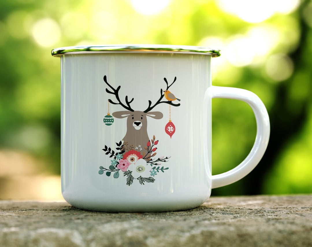 Mug with a picture of a reindeer with ornaments, birds, and flowers on it on a log