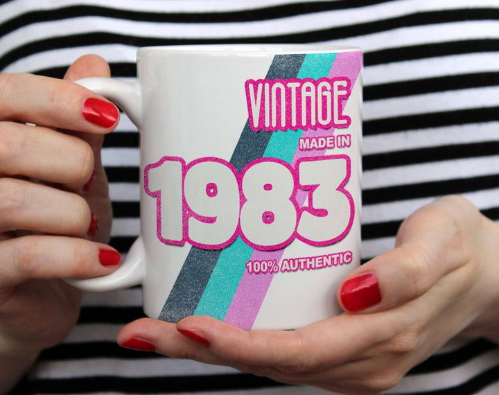 Custom Birth Year 1980's Retro Coffee Mug being held by woman wearing black and white top with red nail polish