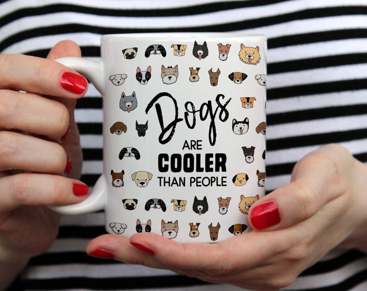 Dogs Are Cooler Than People Mug being held by woman wearing black and white top with red nail polish by hands