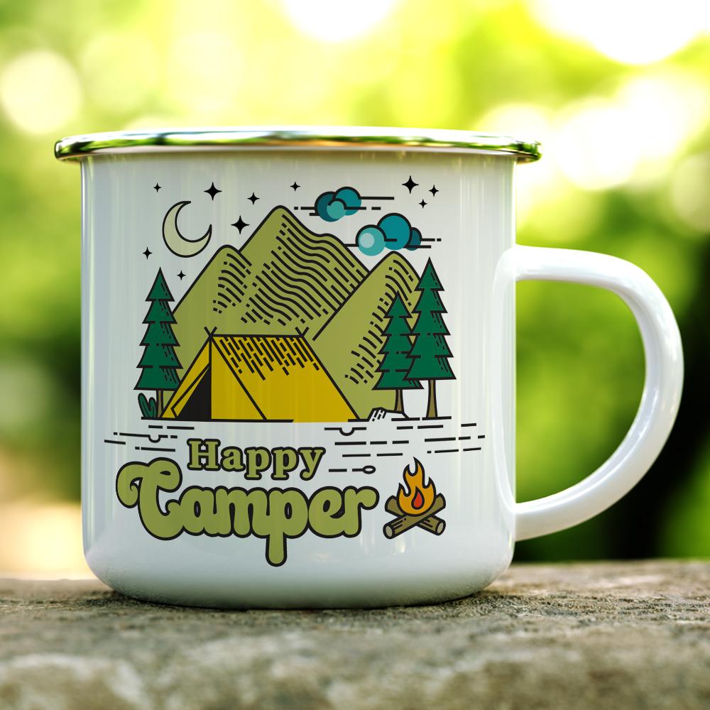 white camp mug with Happy Camper written on it with a tent, trees, and mountains on a log