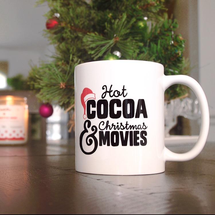 Hot Cocoa & Christmas Movies Mug on the ground near a Christmas tree